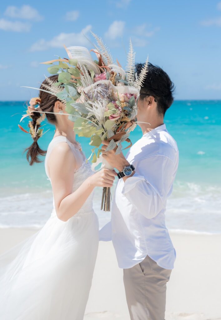 ビーチでウエディングブーケを二人で持つ新郎新婦