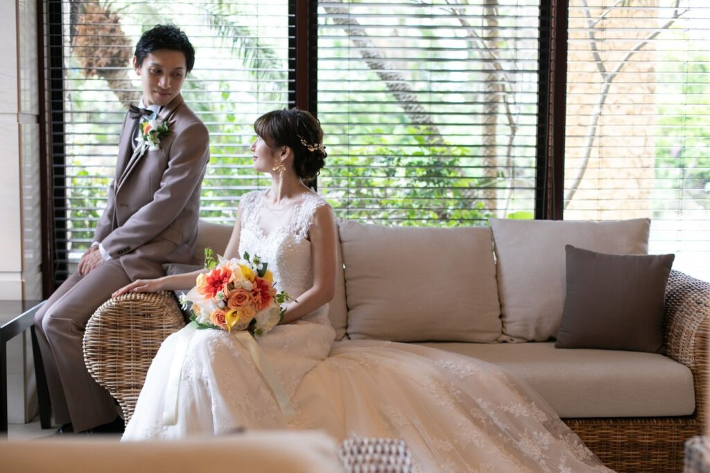 ウエディングブーケをもってホテルのソファーに座っている花嫁と新郎