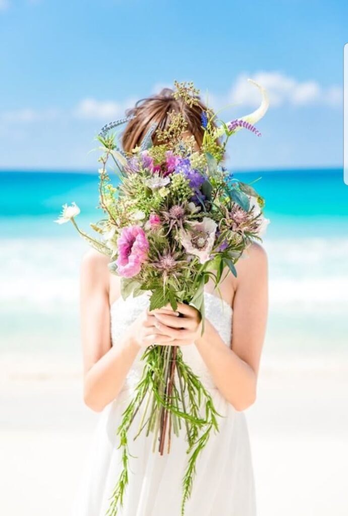 ビーチでドレスを着てウエディングブーケを持っている女性