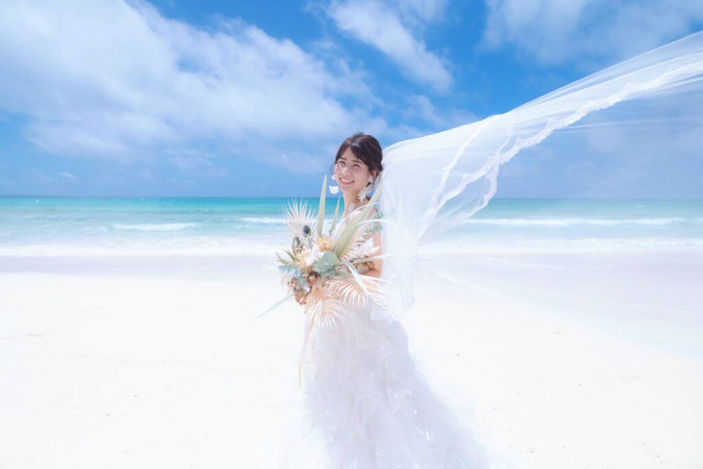 ビーチでウエディングブーケを持って立つ花嫁