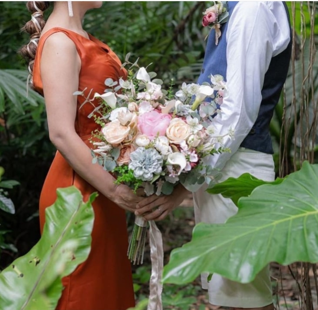 カラードレスの新郎新婦がブーケを持って向かい合う