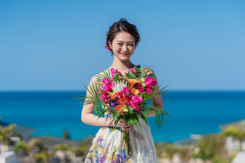 南国花のブーケを持って立ち、微笑む女性